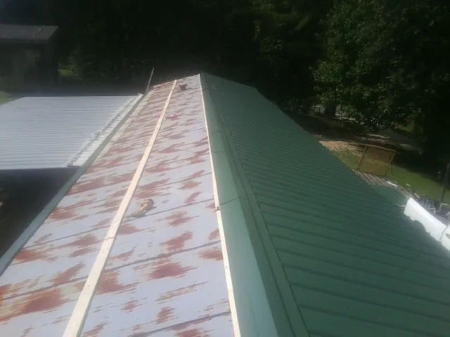 Old rusted panels beside newly installed green metal roofing — Wind Damage Roof Repair by Roofing Brothers in Berkeley Heights