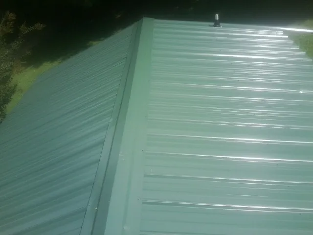 New green metal panels meeting at the ridge of a roof — Flat Roof Repair work by our crew in Berkeley Heights
