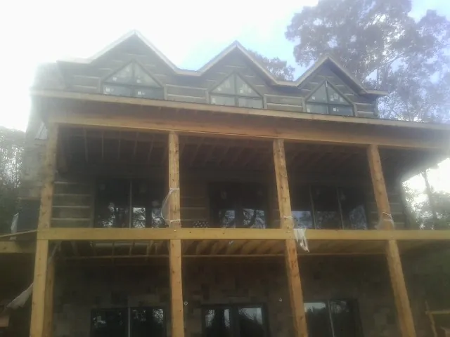 Dormers and porch framing on a large log home under construction — Roof Coating work by our crew in Berkeley Heights