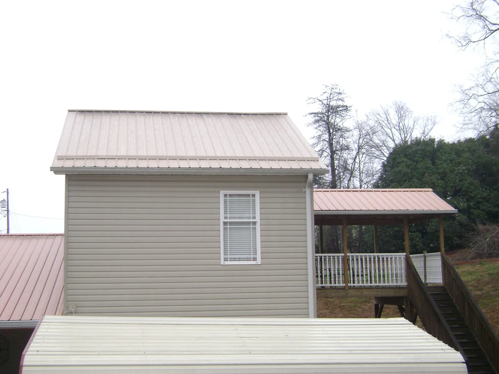 Tan metal roofs on a two story addition and attached porch, from a Roof Replacement job in Berkeley Heights