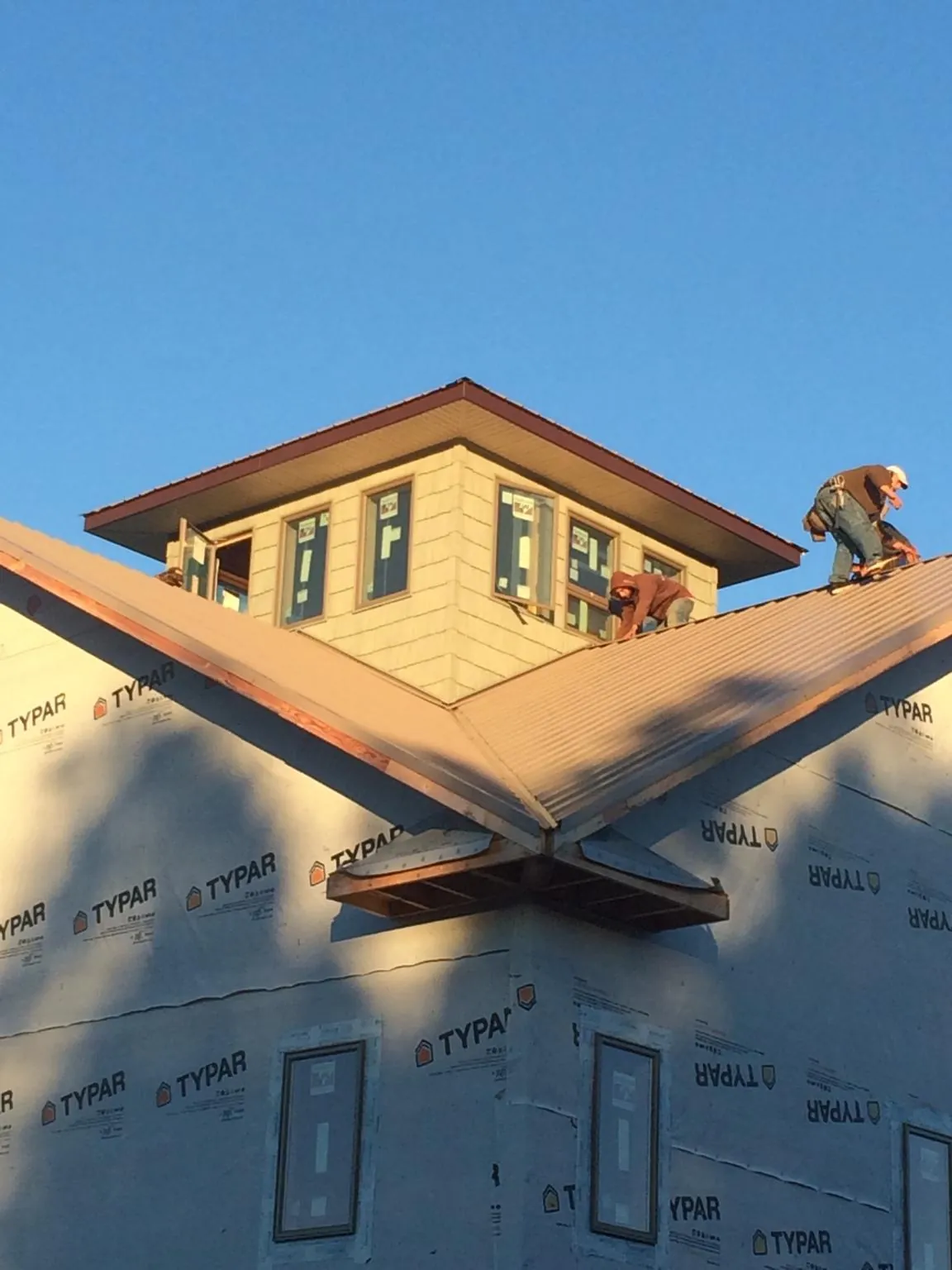 Roofers working around a rooftop cupola on a new metal roof at sunset — Roof Waterproofing in Berkeley Heights by Roofing Brothers